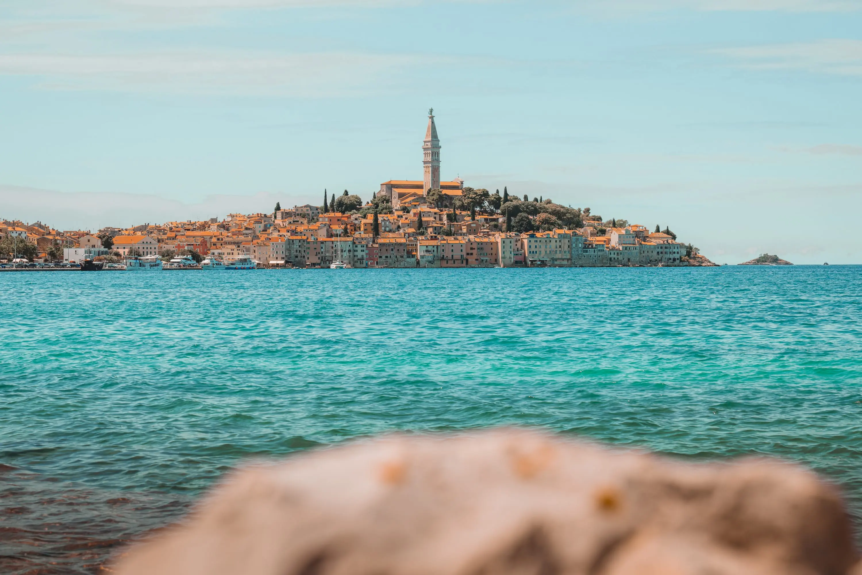 Old town of Rovinj with church tower above turquoise water