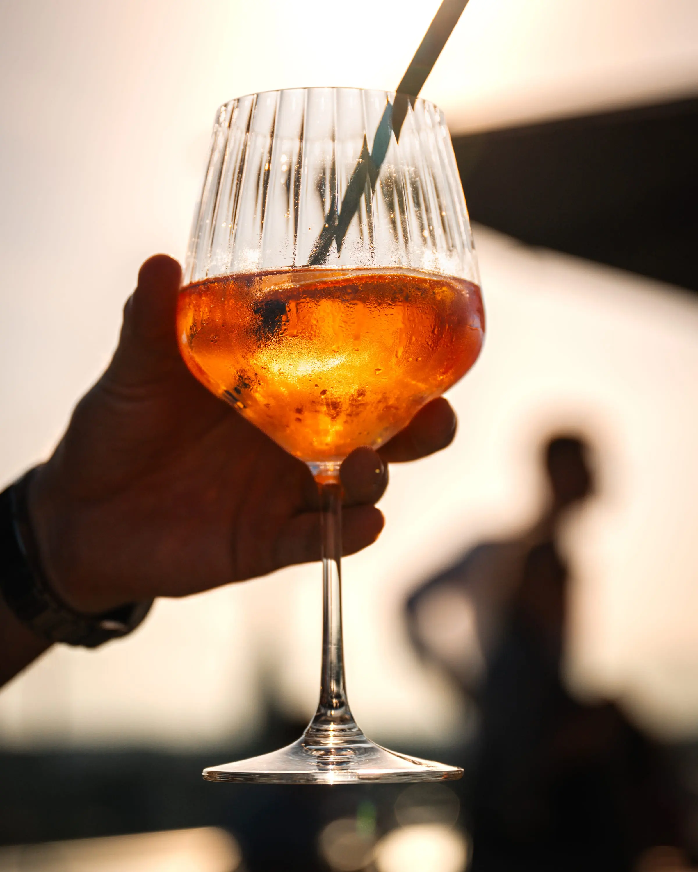 Aperol spritz backlit by the evening sun, a silhouette behind
