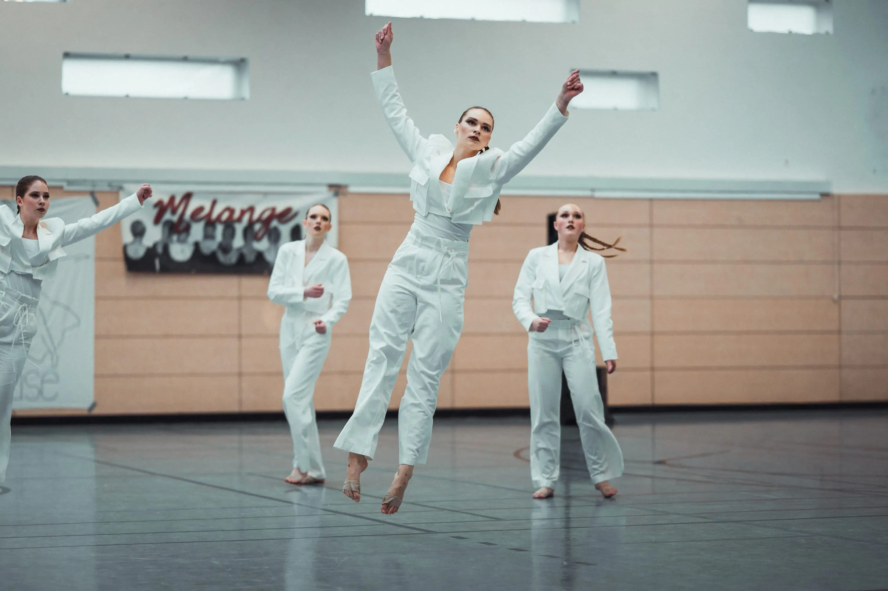 A dancer from the Melange group mid-leap, dressed in white