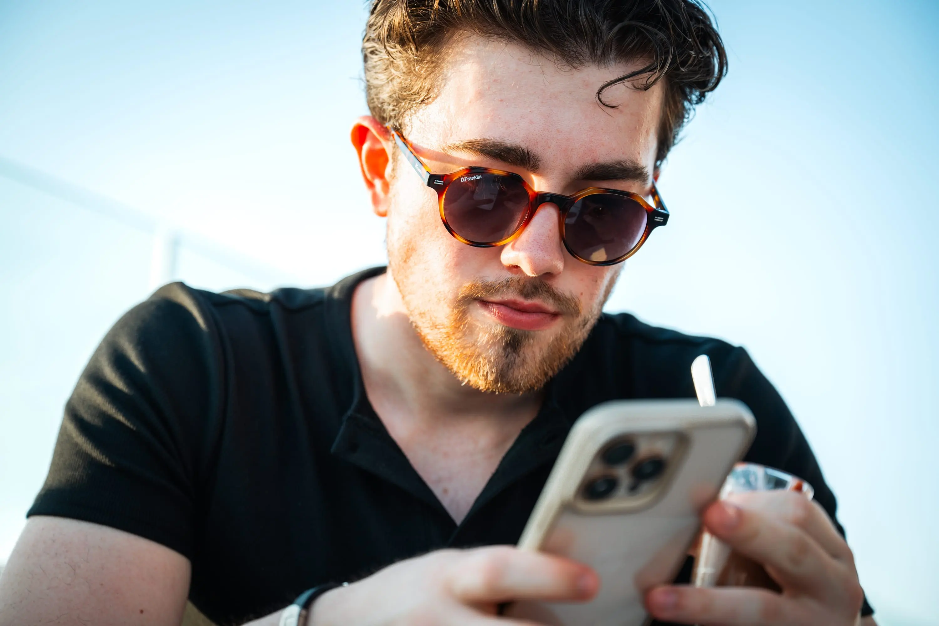 Young man in sunglasses looking at his phone, summer light
