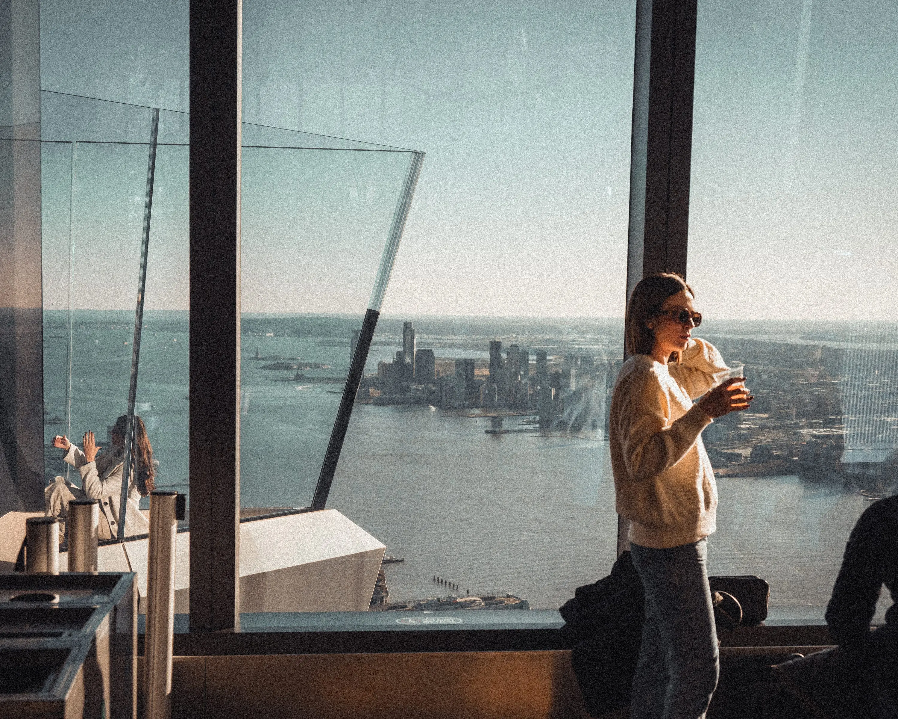A person with coffee at the observation deck high above New York